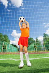 Girl holding football on both straight arms