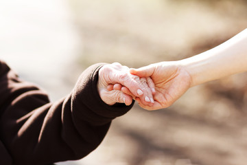 Senior woman holding hands with young caretaker