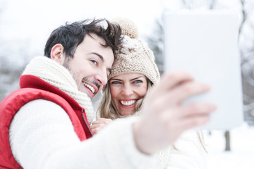 Paar im Winterurlaub macht Fotos mit Tablet Computer - obrazy, fototapety, plakaty
