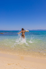 Fototapeta na wymiar Young woman running into sea