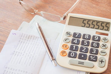 Calculator, pen and eyeglasses on bank account passbook