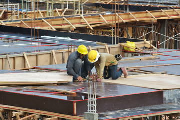 Construction workers fabricating floor slab rebar and formwork