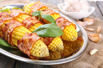 Grilled bacon wrapped corn on table, close-up
