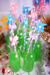 Bottles of drink with straw and sweets on decorative background