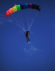 single parachute jumper against blue sky background