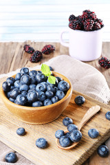 Wooden bowl of blueberries and metal mug of blackberries