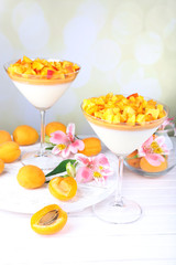 Apricot dessert in glasses on table on bright background