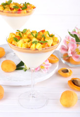 Apricot dessert in glasses on table on bright background