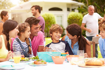 Multi Generation Family Enjoying Meal In Garden Together