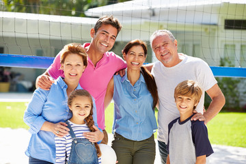 Multi Generation Family Playing Volleyball In Garden