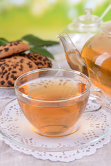 Teapot and cup of tea on table on bright background