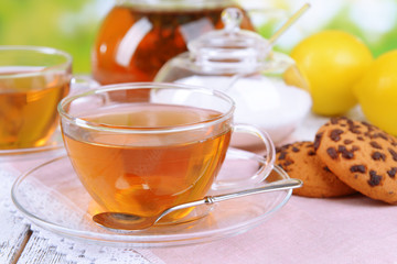 Teapot and cups of tea on table on bright background
