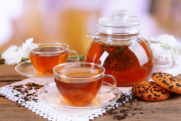 Teapot and cups of tea on table on light background