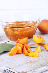 tasty peach jam with fresh peaches on wooden table