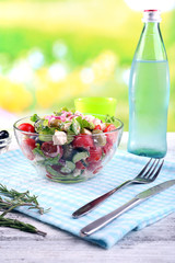 Glass bowl of Greek salad served with water