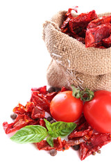 Sun dried tomatoes in sackcloth bag and basil leaves, isolated