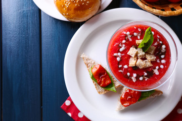 Gazpacho soup in glass bowl, on color wooden background