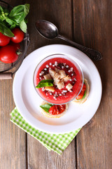 Gazpacho soup in glass bowl, on color wooden background