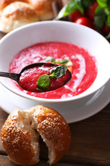Gazpacho soup in spoon and bowl on  wooden background