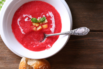 Gazpacho soup in spoon and bowl on  wooden background