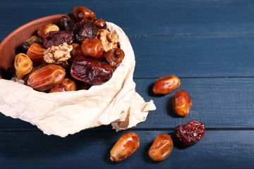 Tasty dates fruits in bowl, on blue wooden background
