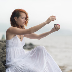 Fototapeta na wymiar Woman holding zen stones in hand with sea background.