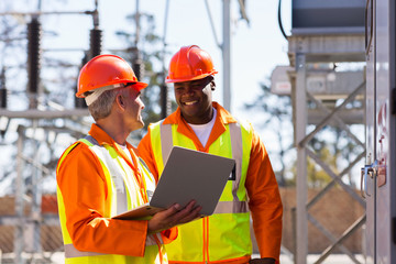 electricians using laptop computer in substation