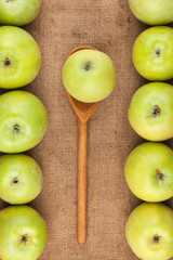 Spoon with green apple lying on the sackcloth among green apples