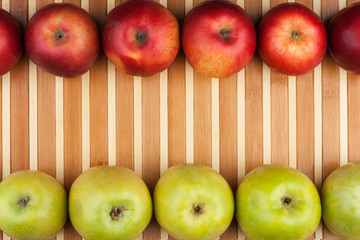 Green and red apples lie on the bamboo mat