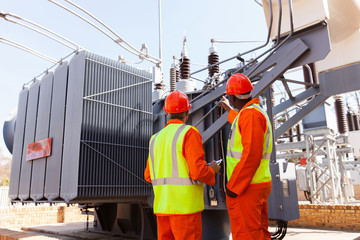 electricians standing next to a transformer
