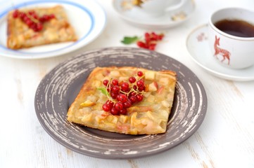 A piece of layered cake with red currant and black tea