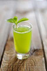 Cucumber juice with mint leaves on a wooden background