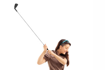 Profile shot of a woman swinging a golf club