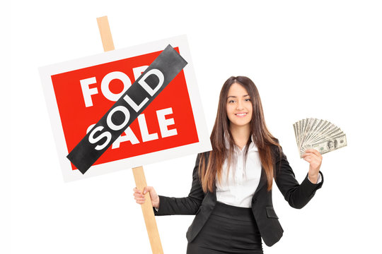 Female realtor holding a sold sign an money