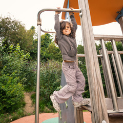 Obraz premium Young girl hanging up in a playground outdoor.