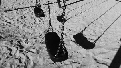 Empty swing with chains on sandy beach