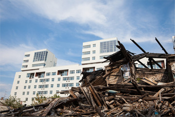 old ruined wooden house on the background of the new buildings