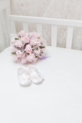 Pink flowers and children's sandals on the white bed