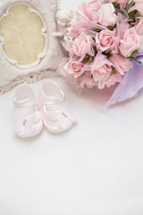 Fototapeta na wymiar Flowers, photoframe and children's sandals on the bed