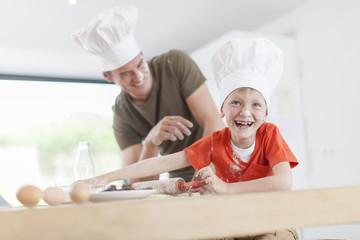 a father and his son preparing a cake in the kitchen