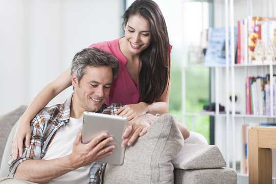 handsome couple using digital tablet on a couch