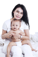 Mother and baby sitting on bed 2