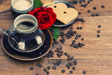 Fototapeta na wymiar Cup of black coffee with red rose flower and heart cake