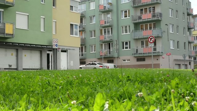 high rise block of flats with green grass a parked cars