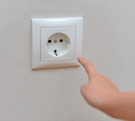 Child sticks his fingers in the socket. Dangerous situation.