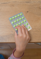 Child takes pack of pills. Dangerous situation.
