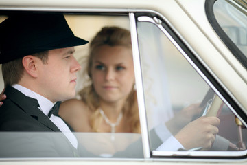 groom and bride in white vintage car