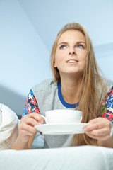 Attractive woman with a cup of coffee on the bed