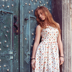 Fototapeta premium fashion red-haired girl standing near a blue wall