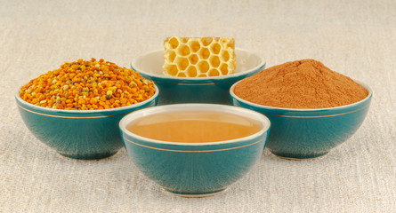 Honey, honeycomb, pollen and cinnamon in bowls